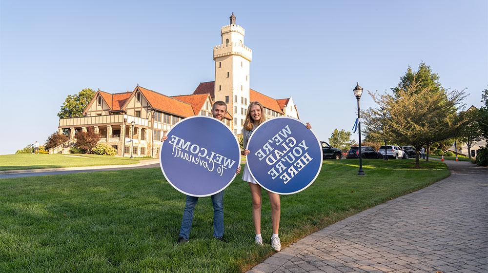 male and female student holding welcome to covenant signs